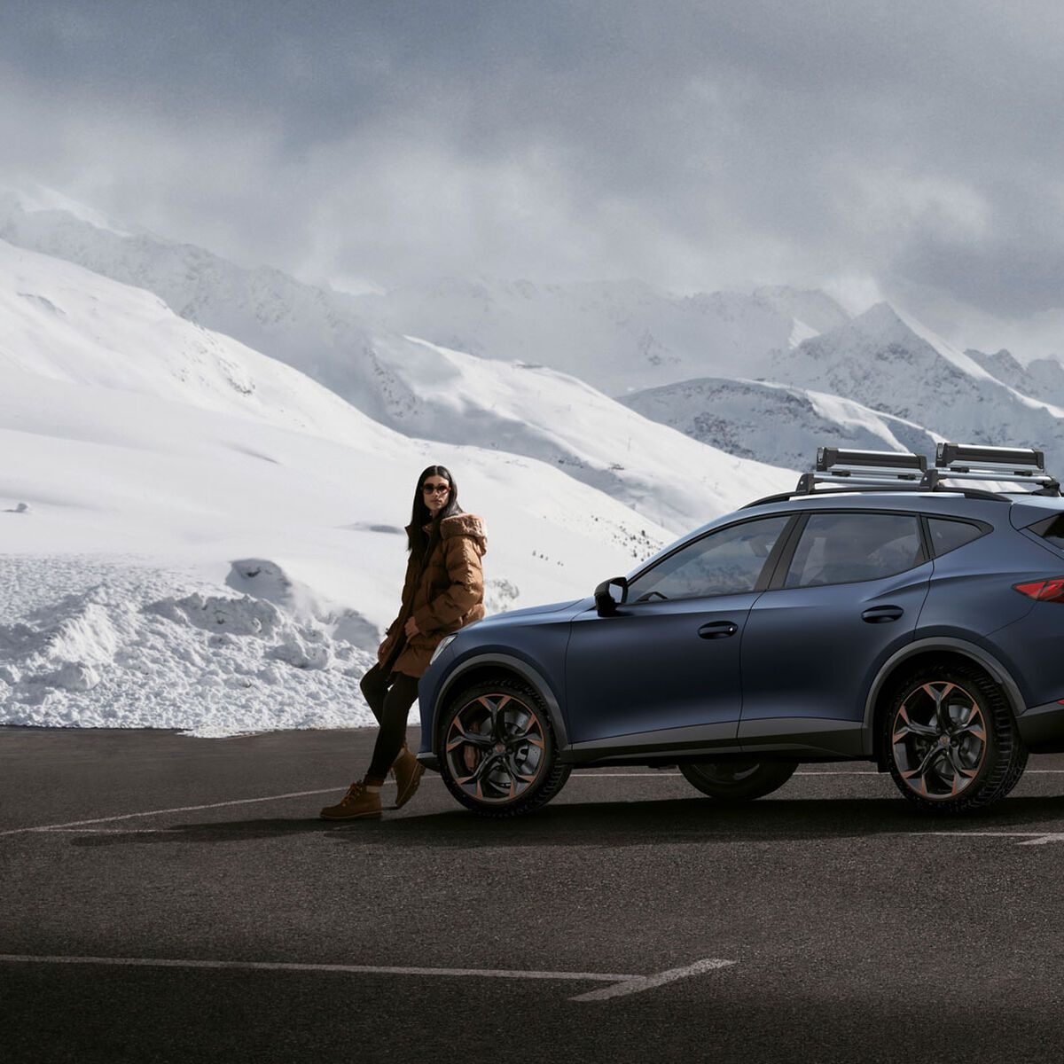 Ein CUPRA Formentor in blau, eine Frau steht davor